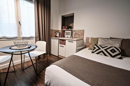 a bedroom with a bed and a table and a kitchen at Les cles du 27 Paris in Paris