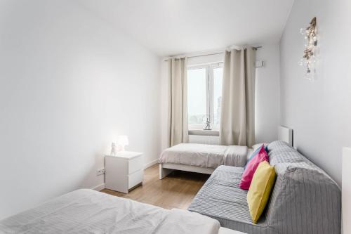 a white bedroom with two beds and a window at Chill Apartments Airport Ursynów in Warsaw