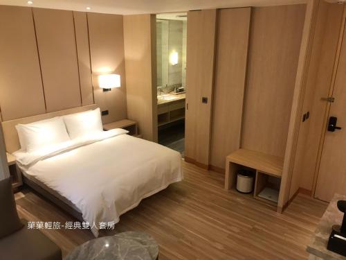 a bedroom with a white bed and a bathroom at 菓菓輕旅 in Puli