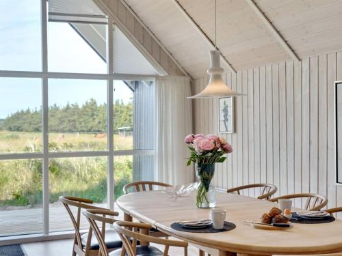 a dining room with a table with flowers in a vase at Holiday Home Allin - 1km from the sea in Western Jutland by Interhome in Mølby