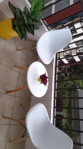 duas cadeiras brancas com uma flor sobre uma mesa em Valley view residence em Nairobi
