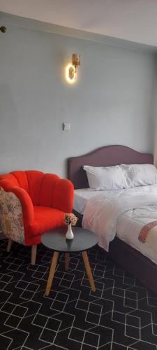 um quarto com uma cama, uma cadeira vermelha e uma mesa em Valley view residence em Nairobi