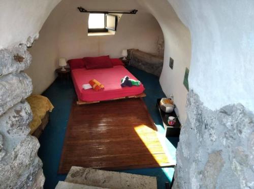 a room with a red bed in a cave at Antico Dammuso Al Tramonto in Pantelleria