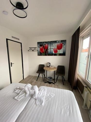 The Diem Amsterdam في أمستردام: غرفة نوم بسرير ابيض مع طاولة وكراسي