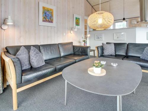 a living room with a black leather couch and a table at Holiday Home Elsbeth - 500m from the sea by Interhome in Lakolk