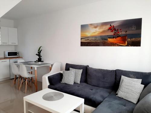 sala de estar con sofá azul y mesa en Apartamenty Sol Mare, en Sarbinowo