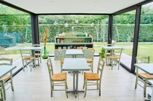 un giardino d'inverno con tavoli e sedie e una cucina di Villa Myosotis a Mirano