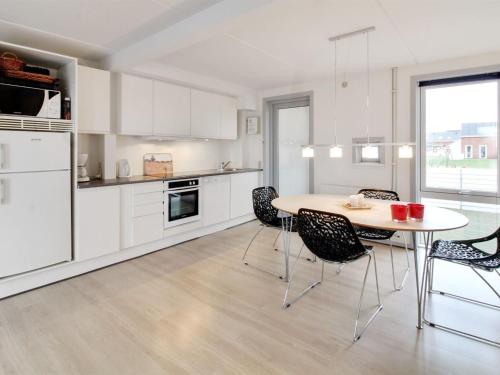 a kitchen with white cabinets and a table and chairs at Apartment Mirija - 2-3km from the sea in Western Jutland by Interhome in Havneby