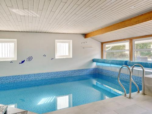 a swimming pool in a house with blue tiles at Holiday Home Cordula - 800m from the sea in Western Jutland in Mølby