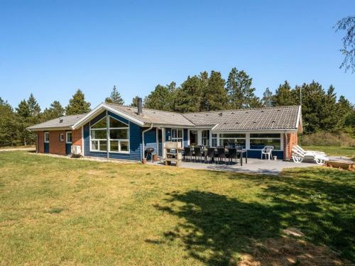a blue house with a patio and a yard at Holiday Home Cordula - 800m from the sea in Western Jutland in Mølby