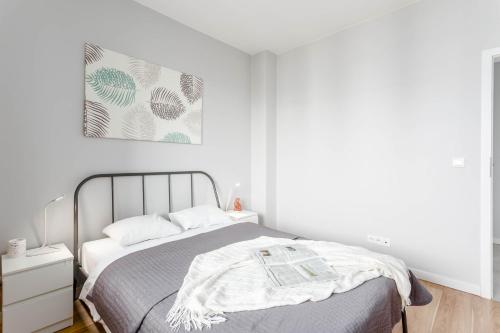 a white bedroom with a bed and a picture on the wall at Chill Apartments Airport Ursynów in Warsaw