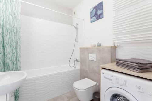 a bathroom with a toilet and a sink and a washing machine at Chill Apartments Airport Ursynów in Warsaw