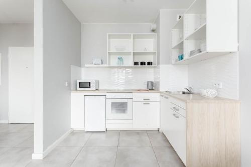 a white kitchen with white appliances and white cabinets at Chill Apartments Airport Ursynów in Warsaw
