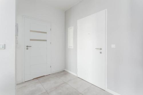 a white room with four doors and a tiled floor at Chill Apartments Airport Ursynów in Warsaw