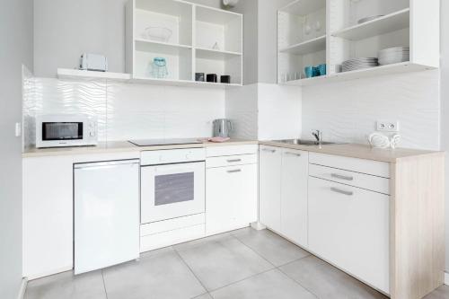 a white kitchen with white cabinets and white appliances at Chill Apartments Airport Ursynów in Warsaw