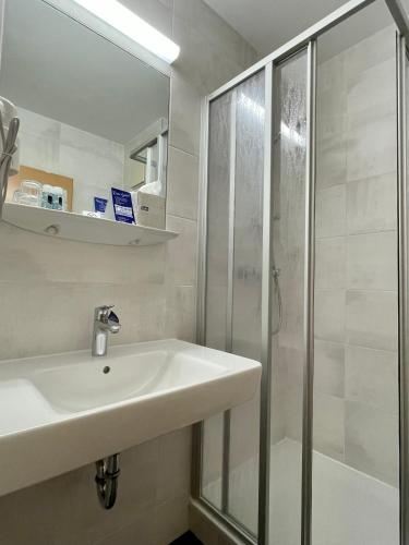 a white bathroom with a sink and a shower at Businesshotel Berlin in Berlin
