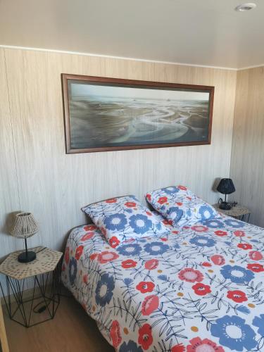 une chambre avec un lit avec une couette fleurie dans l'établissement Agréable Tiny house à la campagne, à Coulombs