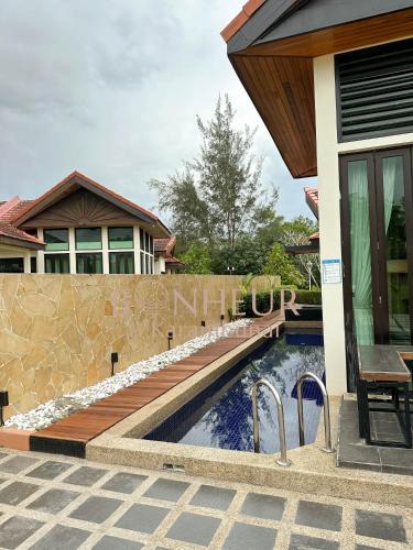 a swimming pool next to a house with a fence at Bonheur at Karambunai in Kota Kinabalu