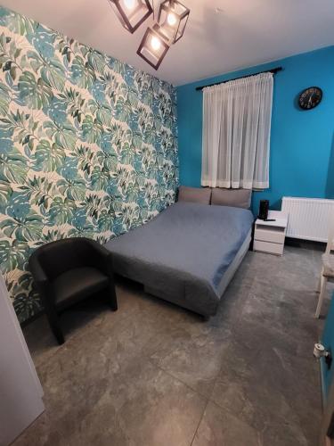 a bedroom with a bed and a chair and blue walls at DEIZY Apartamenty in Wągrowiec