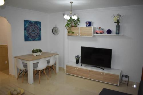 ein Wohnzimmer mit einem Tisch und einem TV sowie einem Tisch und Stühlen in der Unterkunft La casita de ¨Pueblo Rocio¨ in Torre del Mar