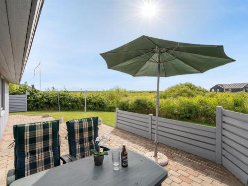 een tafel met een groene parasol op een patio bij Holiday Home Elise - 800m from the sea in Western Jutland by Interhome in Lakolk