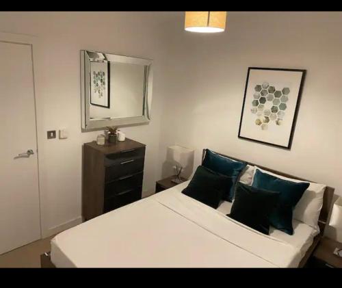 a bedroom with a white bed with blue pillows and a mirror at Luxurious 2 bedroom apartment in Canary Wharf in London