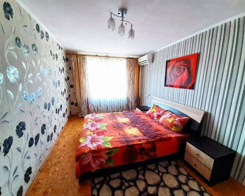 - une chambre avec un lit doté d'une couette rouge et d'une fenêtre dans l'établissement ApartPoltava 2-room apartment near UMSA, ПДМУ, Звітна документація для відрядження, à Poltava