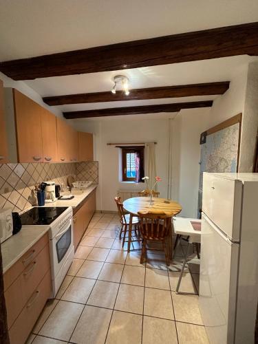 une cuisine avec une table et un réfrigérateur blanc dans l'établissement La Grenouille, à Turckheim