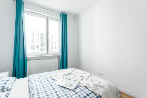 a bedroom with a bed with blue curtains and a window at Chill Apartments Airport Ursynów in Warsaw