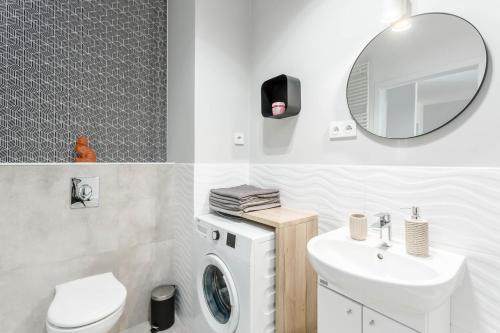 a bathroom with a sink and a toilet and a mirror at Chill Apartments Airport Ursynów in Warsaw