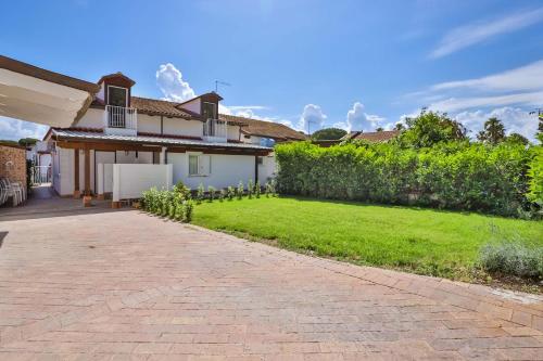 a house with a brick driveway in front of a yard at Il Pineto Paestum Food & Rooms in Paestum