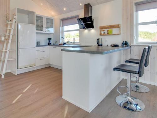 a kitchen with white cabinets and a bar with a stool at Holiday Home Minke - 2-2km from the sea in Western Jutland in Bolilmark