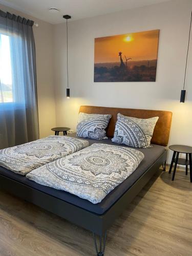 ein Bett in einem Schlafzimmer mit 2 Tischen und einem Gemälde in der Unterkunft Moderne Wohnung in Heskem bei Marburg (Lahn) 