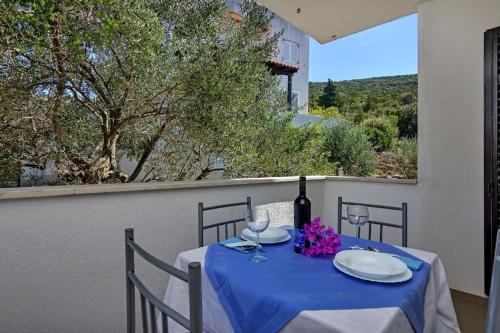 einen Tisch mit einem blauen Tischtuch und einer Flasche Wein in der Unterkunft Apartments Igor in Gdinj