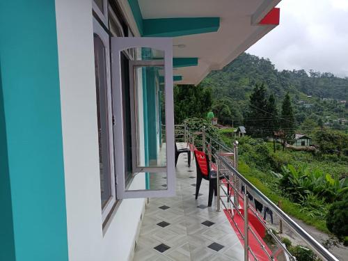 a balcony with red chairs and a view of a mountain at Mairung Gaon Farm Stay in Rishop