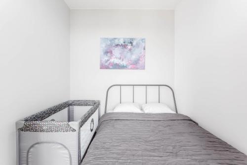 a white bedroom with a metal bed and a painting at Chill Apartments Airport Ursynów in Warsaw