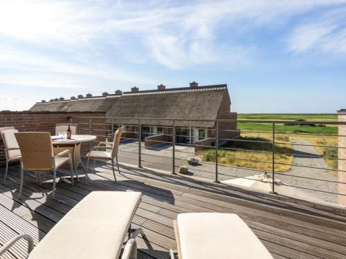 a deck with tables and chairs and a view of a building at Apartment Helgo - 250m from the sea in Western Jutland by Interhome in Sønderby