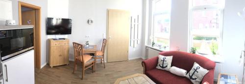 ein Wohnzimmer mit einem roten Sofa und einem TV in der Unterkunft Haus Breslau in Borkum