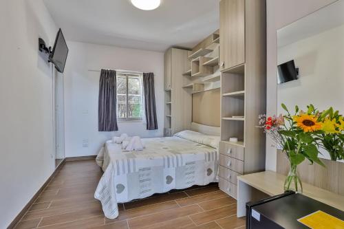 a small bedroom with a bed and a vase of flowers at Il Pineto Paestum Food & Rooms in Paestum
