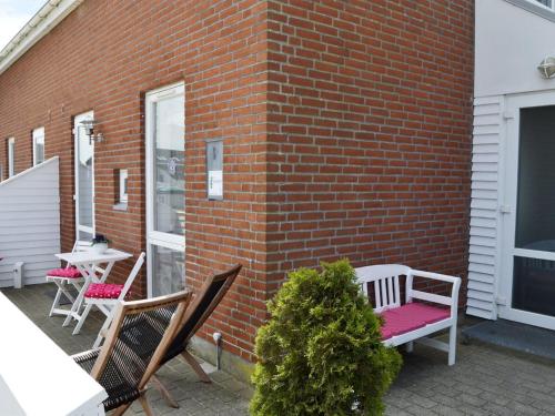 a brick wall with two chairs and a table on a patio at Apartment Svava - 2-3km from the sea in Western Jutland by Interhome in Sønderby