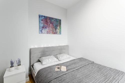 a white bedroom with a bed with a gold bow on it at Chill Apartments Airport Ursynów in Warsaw