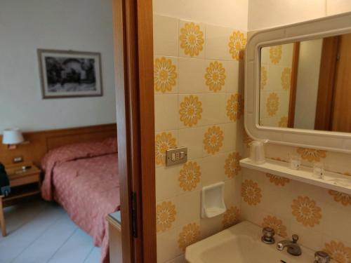 a bathroom with a sink and a mirror and a bed at LH Hotel Del Lago Scanno in Scanno