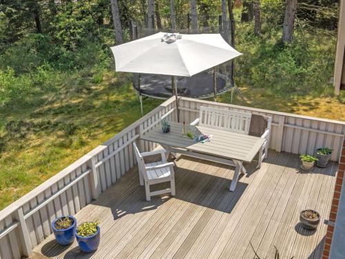 a wooden deck with a table and an umbrella at Holiday Home Ridir - 3-5km from the sea in Western Jutland by Interhome in Rømø Kirkeby