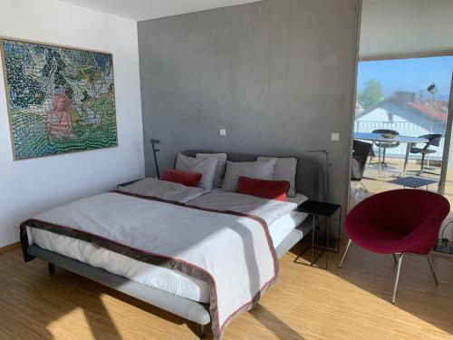 a bedroom with a large bed with a red chair at Trilogie am See Wohnung Taube in Stetten