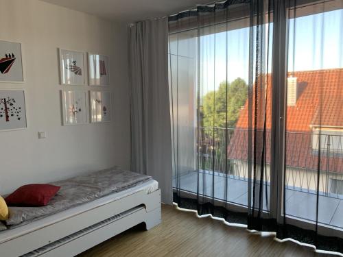a bedroom with a bed and a large window at Trilogie am See Wohnung Schmetterling in Stetten