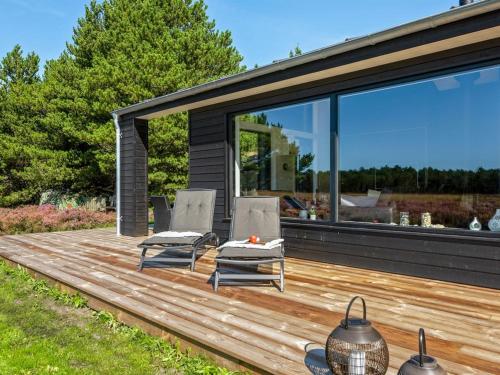 a wooden deck with two chairs and a table at Holiday Home Tea - 2-7km from the sea in Western Jutland by Interhome in Bolilmark