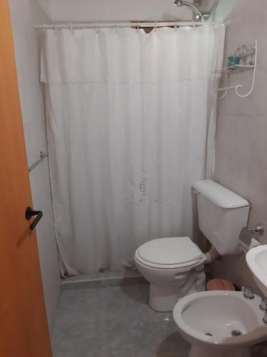 baño con aseo y cortina de ducha blanca en Cabaña Pampa en Esquel