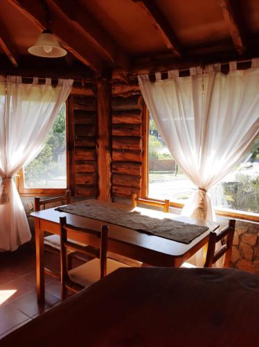 埃斯克爾的住宿－Cabaña Pampa，一间设有桌子和两个窗户的房间
