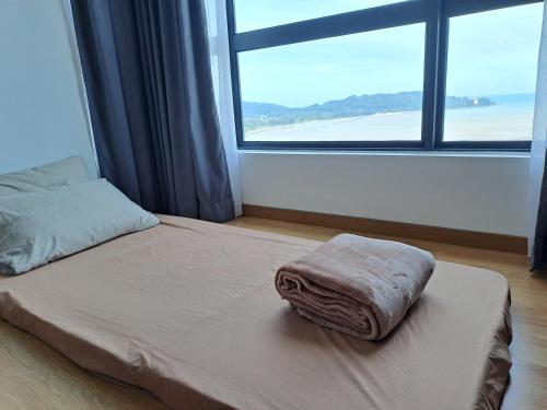 a bed with a towel on it in a room with a window at Best Moments suite 1 in Kuantan