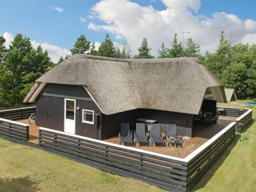 une maison avec un toit de chaume sur une terrasse dans l'établissement Holiday Home Patrik - 1-4km from the sea in Western Jutland by Interhome, à Blåvand